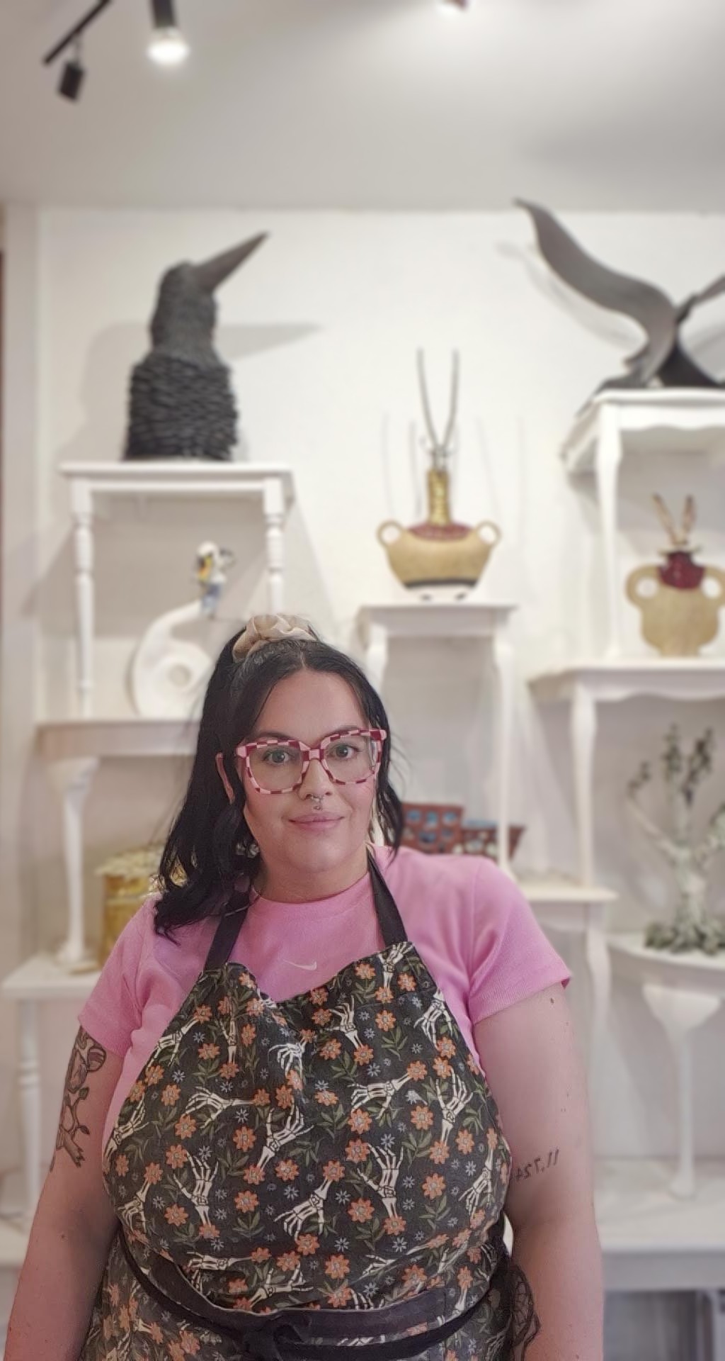 Antonia in her studio, smiling in front of shelves of handmade ceramics